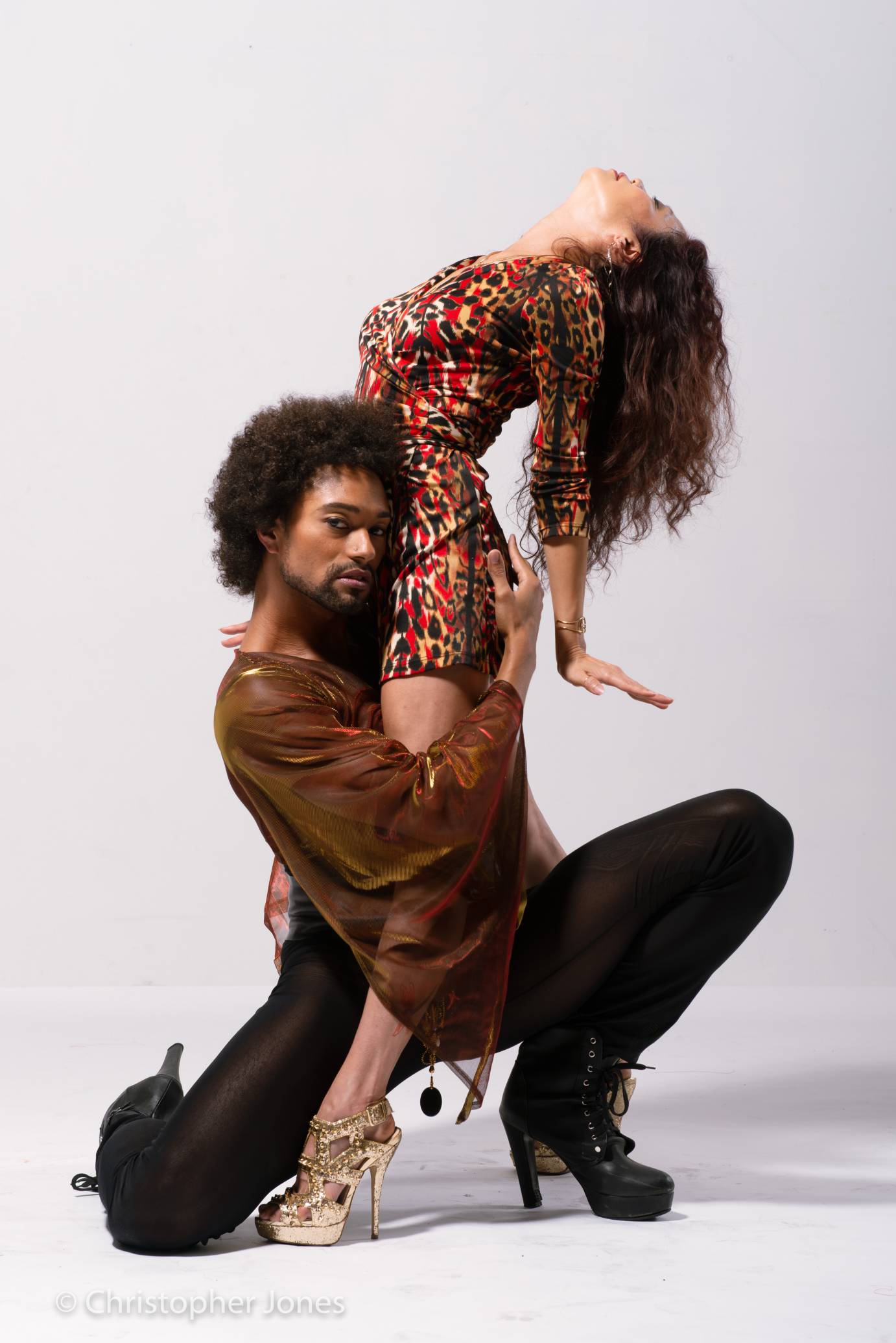Abdiel kneels as Kristine backbends; both are in heels