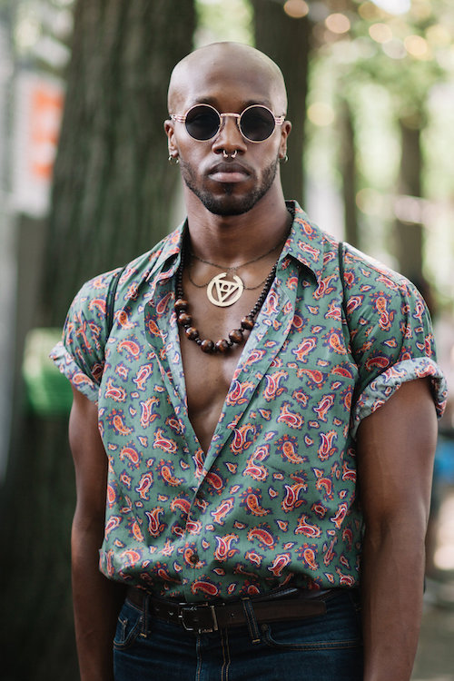 J. Bouey wears round wire rim sunglasses and pink and green patterned shirt.