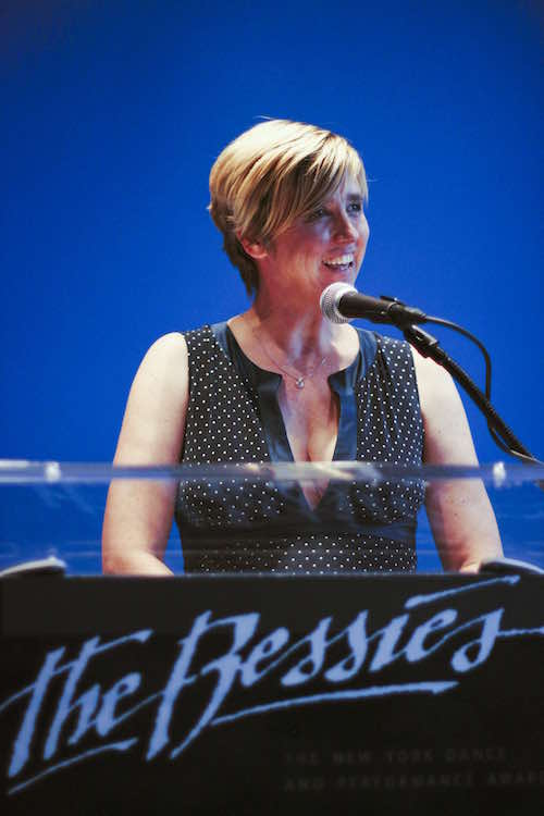 Lucy Sexton stands at a podium that reads The Bessies.