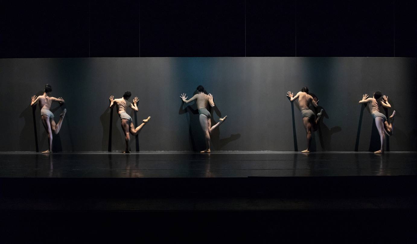 Five dancers with the their backs to the audience flick their legs