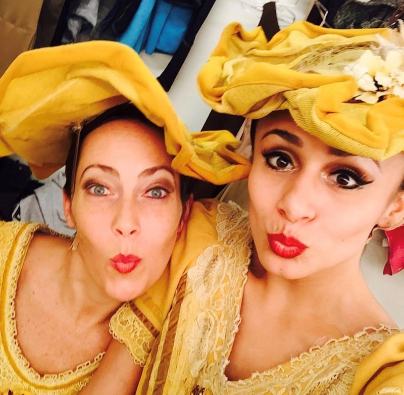 A selfie of two Ailey dancers in yellow dresses and ornate hats featured in Alvin Ailey's iconic Revelation