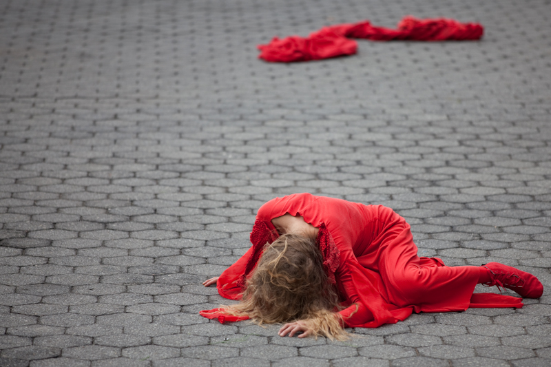 A woman in red lays on the ground. We can't see her face.