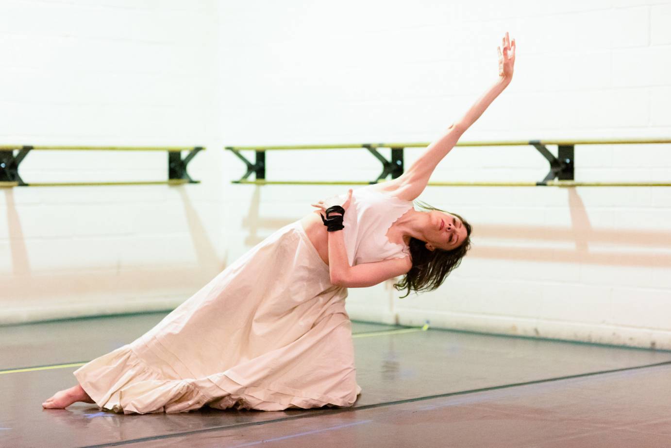 In a white dress, Alison Clancy tips her body sideways