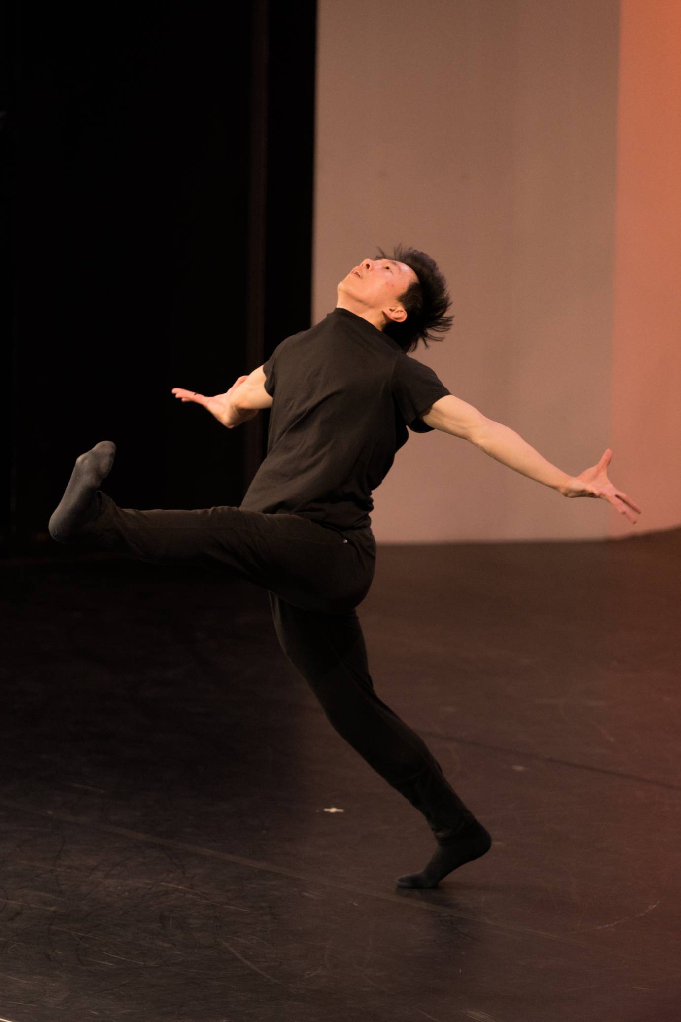 Dancer with one leg extended in the air in front of him, arms outstretched