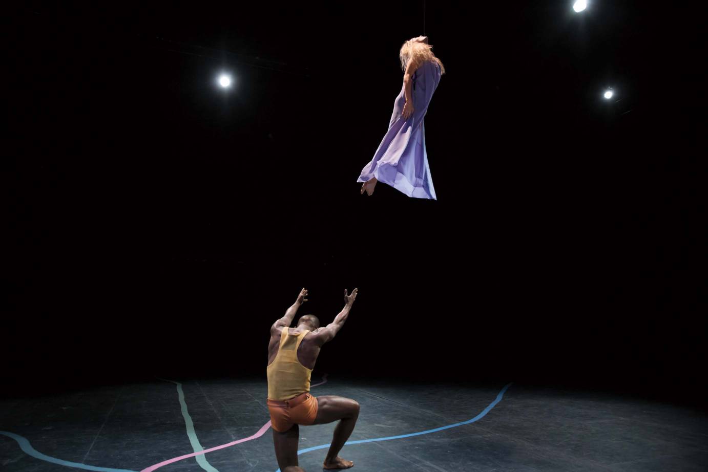 A male dancer propelling a female dancer clad in a purple dress into the air.