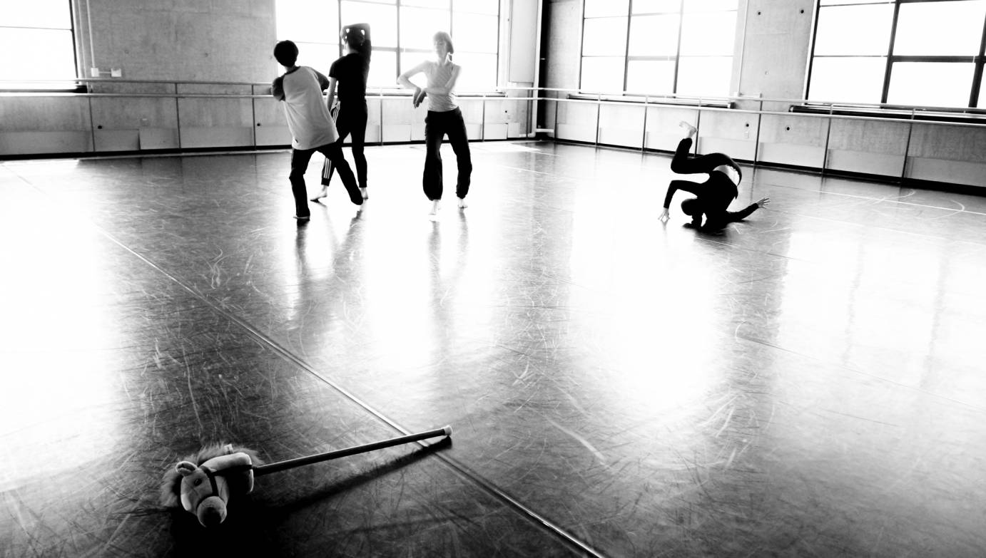 Four dancers move as a stick horse lays on the floor