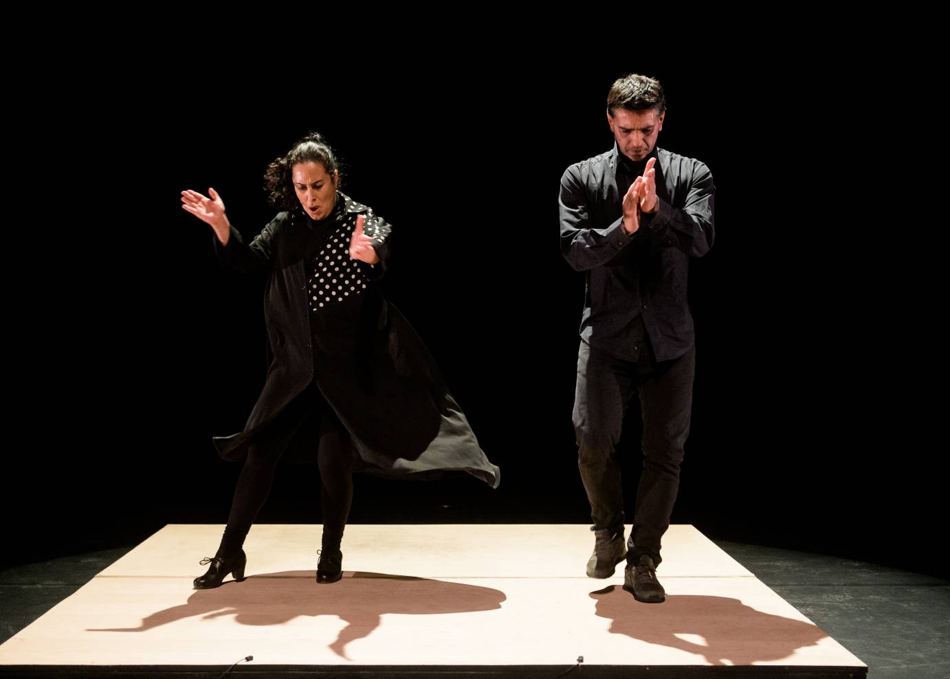 A man and a woman clap their hands and stamp their feet in a flamenco performance