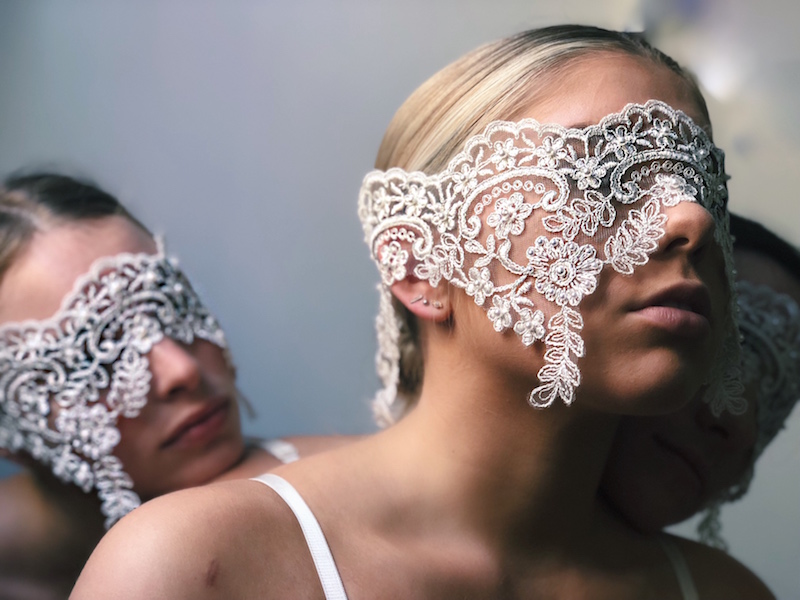 Two women wear lace over their eyes like a blindfolds