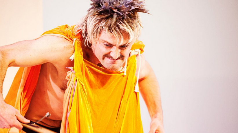 Dancer Sean Donovan wearing a turmeric-colored tunic and grinning/grimacing.