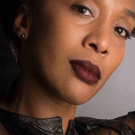 head shot of Francesca Harper, not full face, forehead cropped out, a black woman with large dark eyes, and burgundy lips, wearing a tiny gold earring, stares out at us thoughtfully