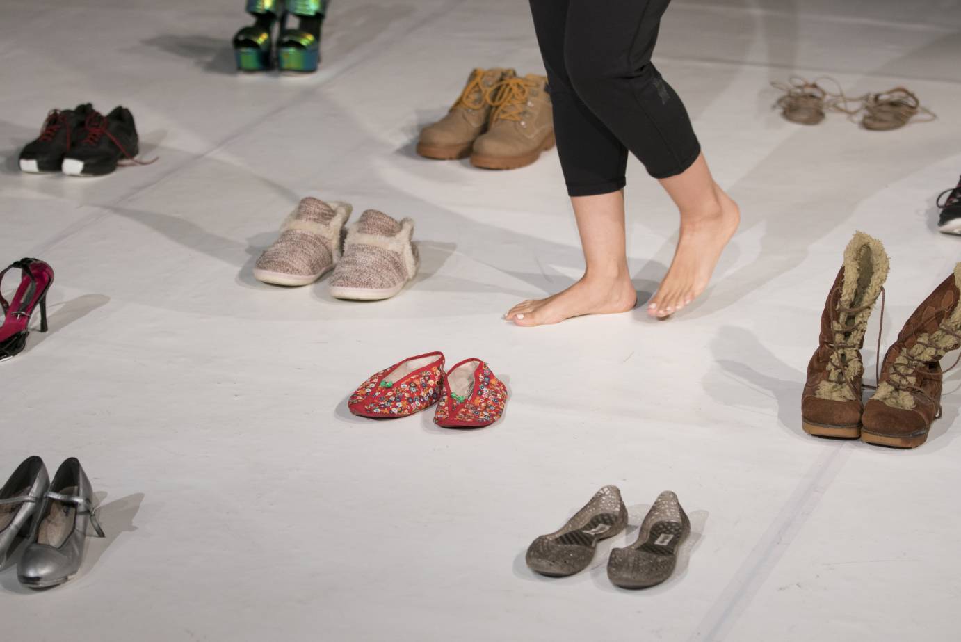 Woman's legs among a grid of paired shoes