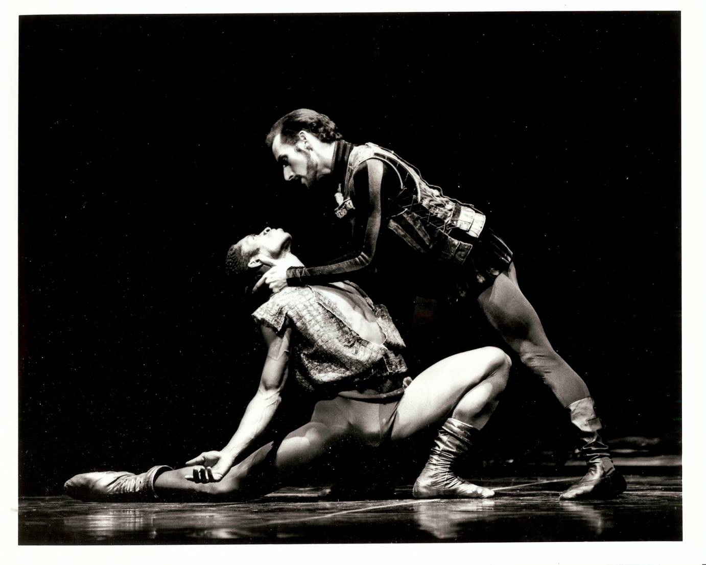 A dramatic picture of Iago grabbing a kneeling Othello's head