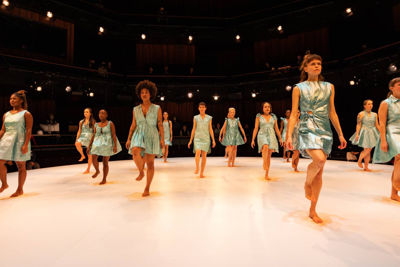 an army of women in crinkeled aqua dresses march towards us 