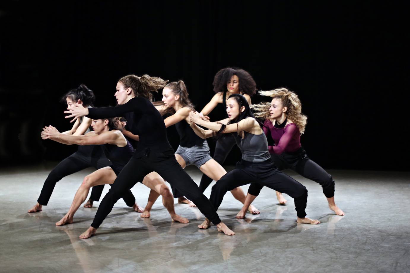 Group of female dancers clasp their hands while looking fierce