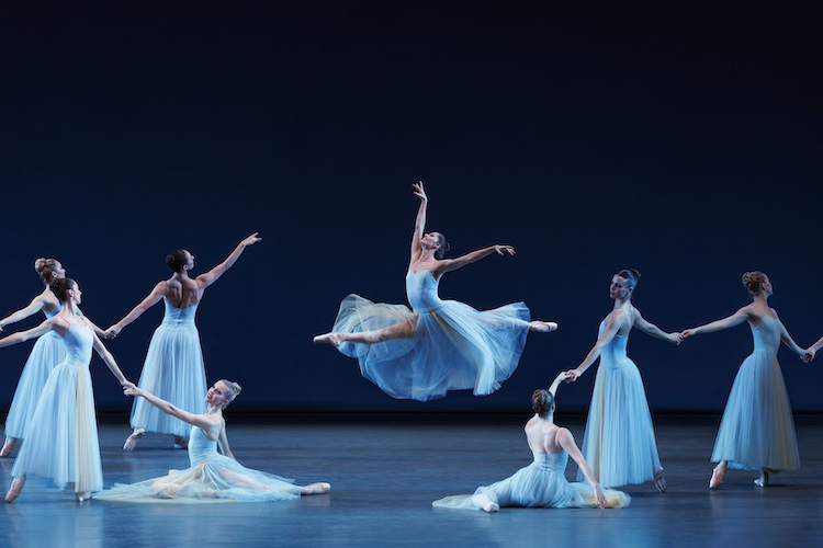 Balanchine's first American ballet, arranged in a beautiful collection of poses, women in romantic blue tutus hold hands in varying stationary reaching poses, a central figure... is aloft in the middle of a grand jete..