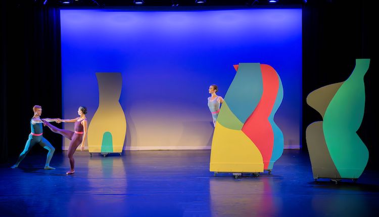 three multi-colored abstract set pieces provide the landscape for three dancers in bright unitards to play.