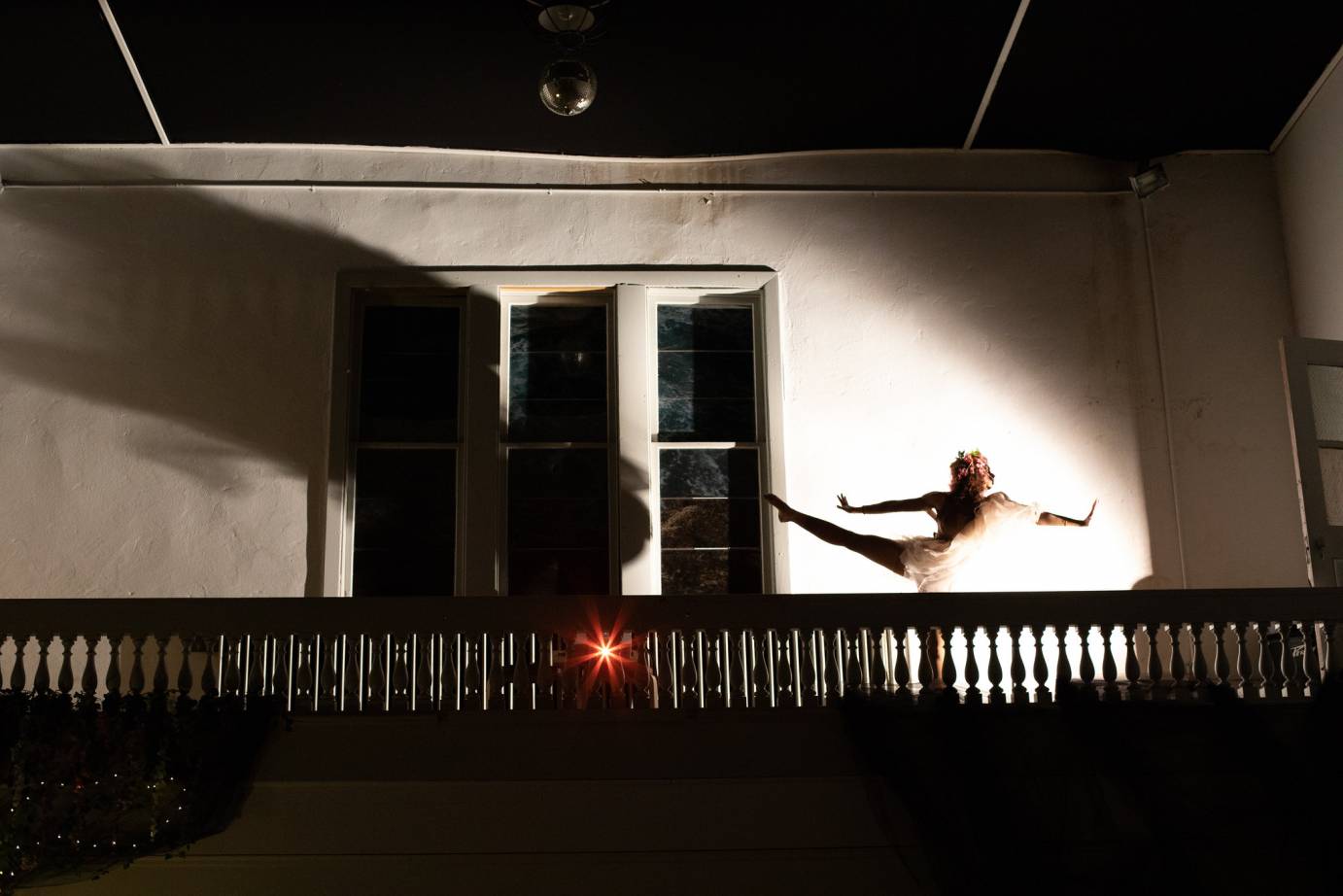 A woman extends her limbs in shadows on a balcony
