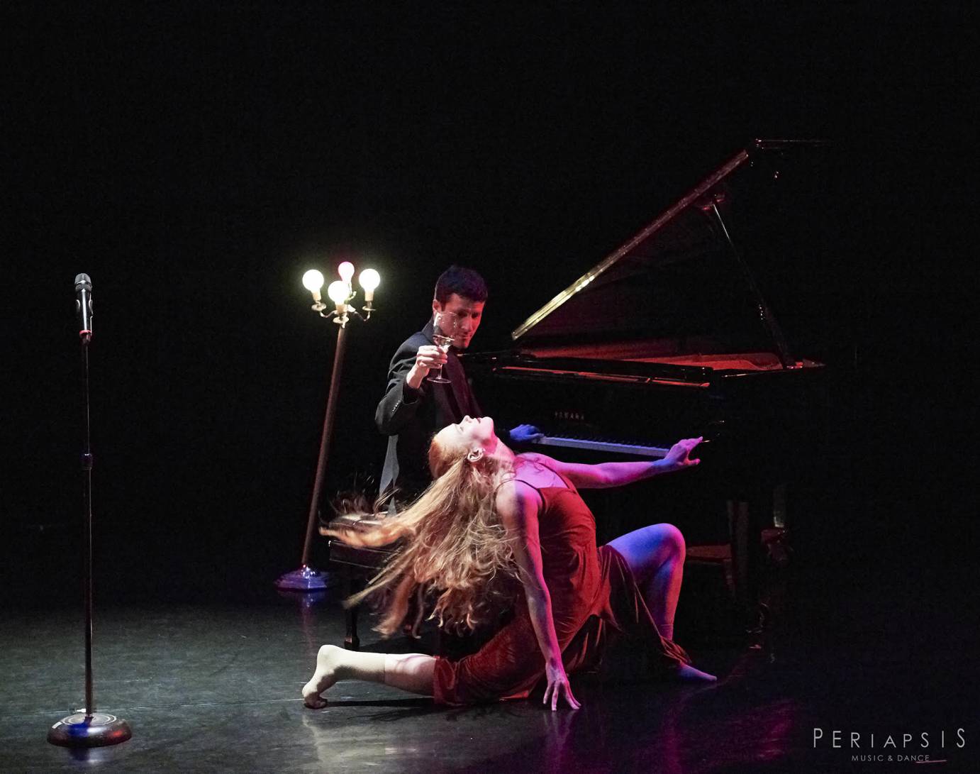 A man at a piano offers a lunging woman wine