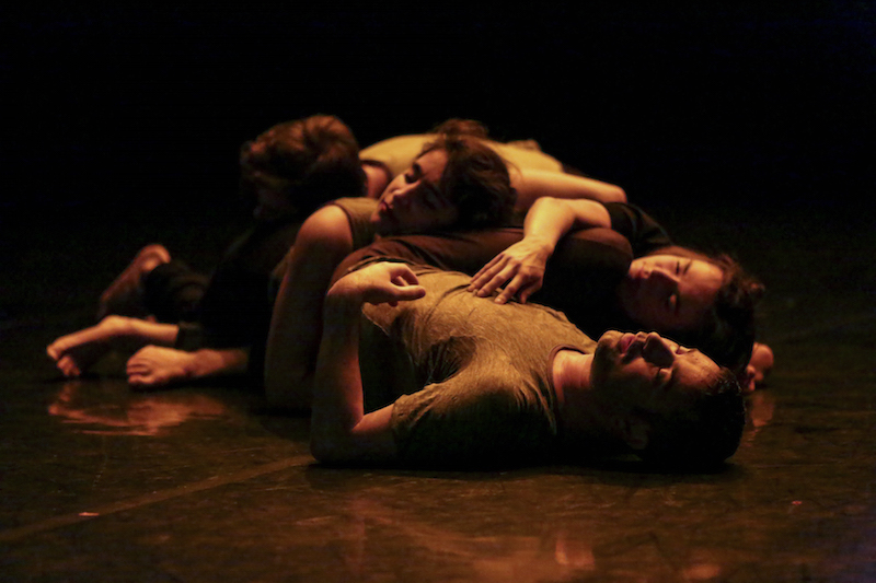 Dancers lay in a heap together. Their limbs tangled and torso draping over one another's.