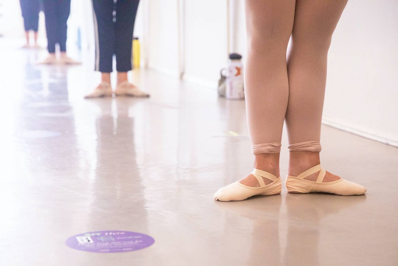 Picture of students' legs in first position standing at the barre
