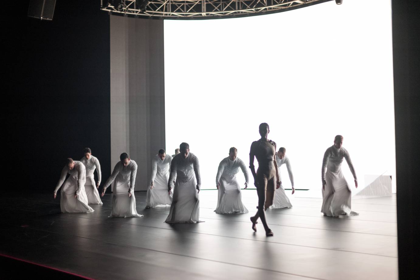 One female dancer in front of eight men in white