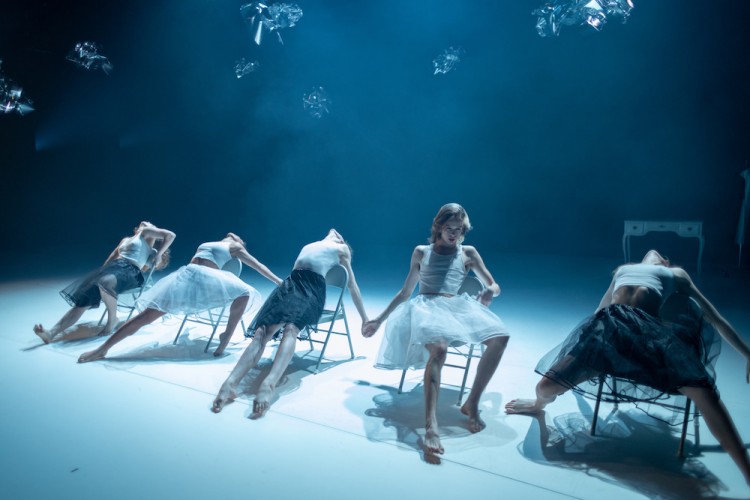 the stage shimmers as 5 dancers are sprawled out on folding chairs ... everyone is wearing white tight tops and tulle skirts a center couple holds hands
