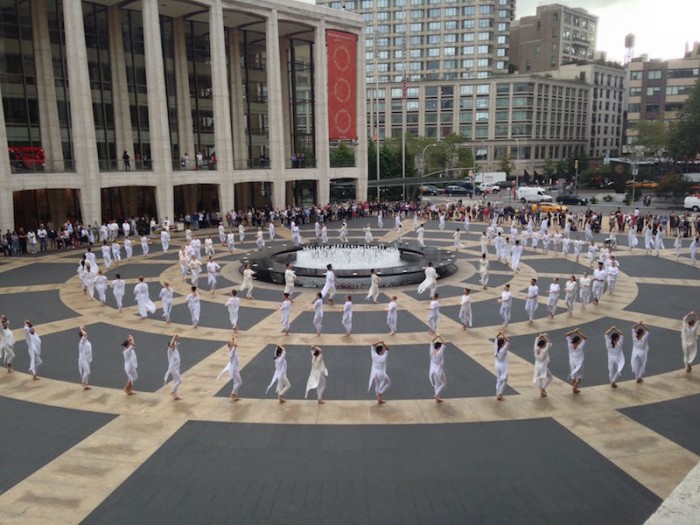 Some dancers sit crosslegged while other lean against the plaza's center fountain