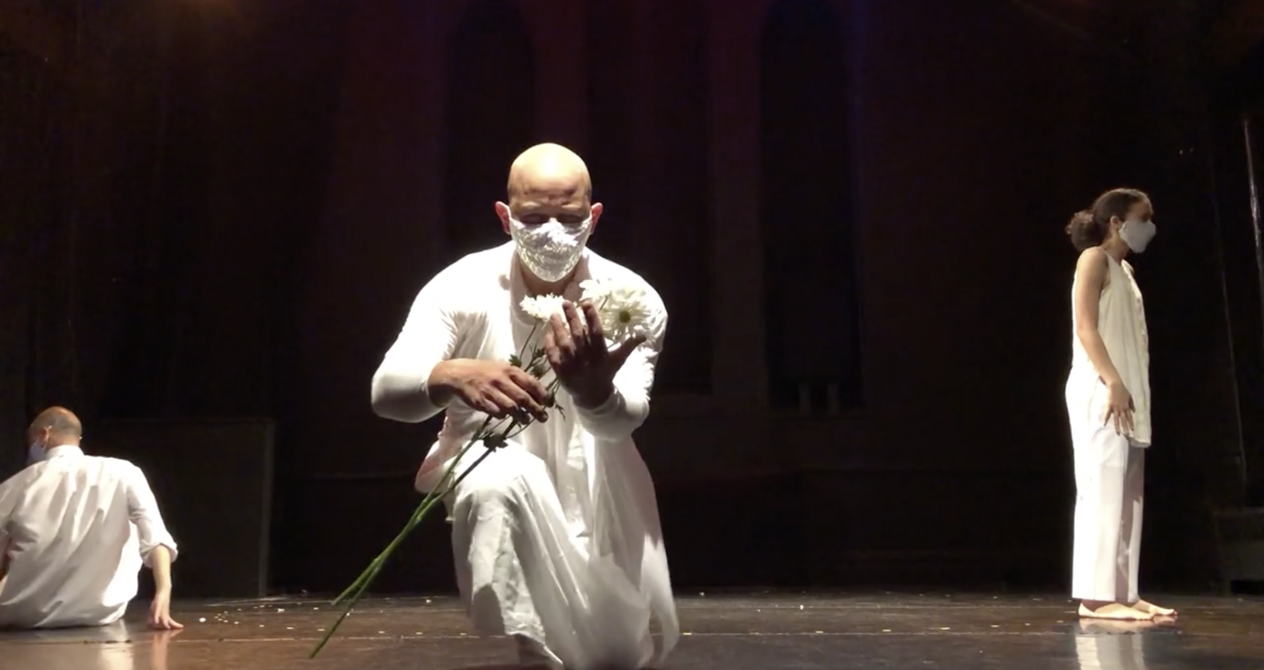 Alethea Pace, Arthur Aviles, and Richard Rivera dance on a black marley floor illuminated by stage lighting. They wear all white garb including a white face covering.