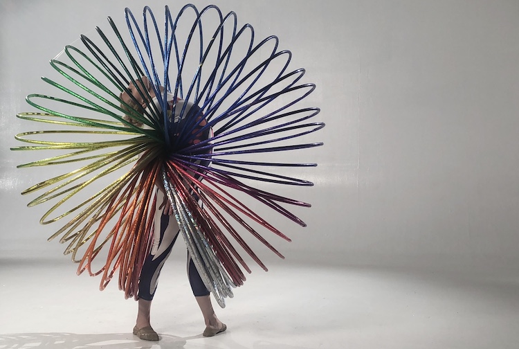 Ellie Steingraeber in a publicity shot in a white studio. She is wearing an enormous mult colored slinky costume... surprising