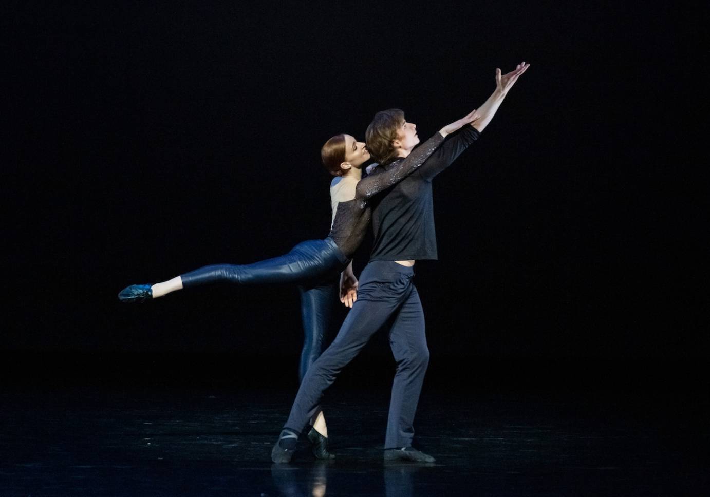 A man and a woman strike a jazzy pose, one arm lifted high