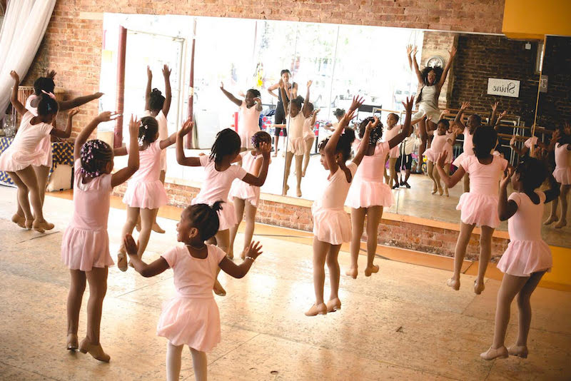 Young girls in pink leotards dance in a studio