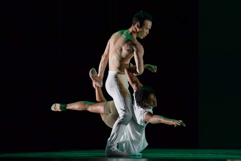 Kanji holds dancer Jacuelin Harris between his legs. She is a few inches from the floor.