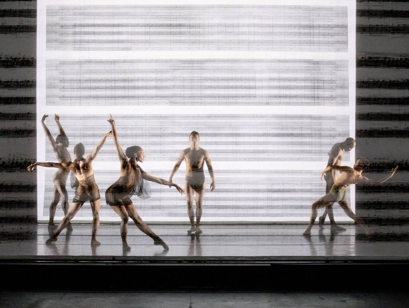 Dancers in contorted poses against smudgy sheet music