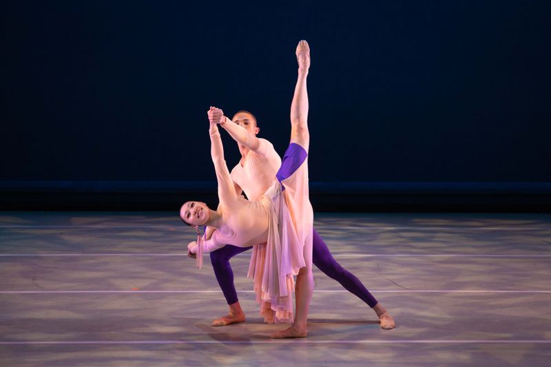 a male person supports a female person as she stands on leg with the other leg in a high arabessque 