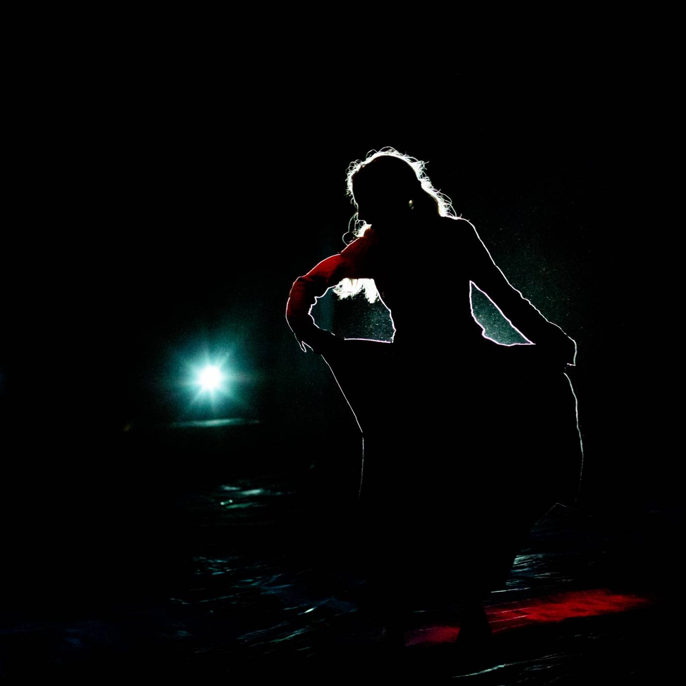 Against dark lighting, Alison Clancy holds the skirt of her red dress