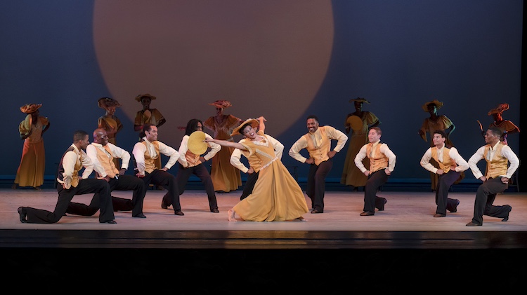 a scene of jubliation and praise as a church woman bedecked in yellow gown and sunday best hat is surrounded by church going men on their knees who've caught her spirit