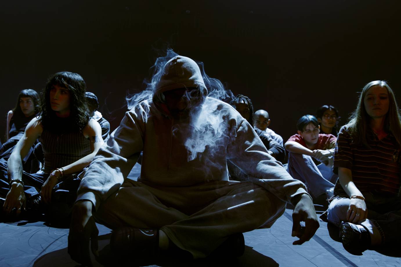 Seated youth, the tops of their heads softly lit, vape.