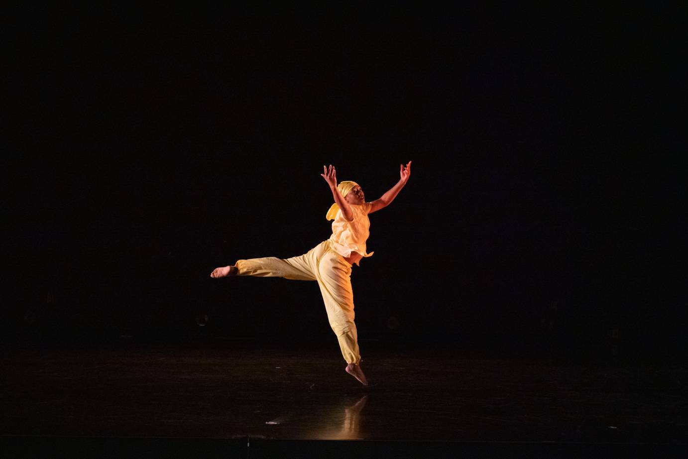 woman dancer in a leap, arms extended skyward