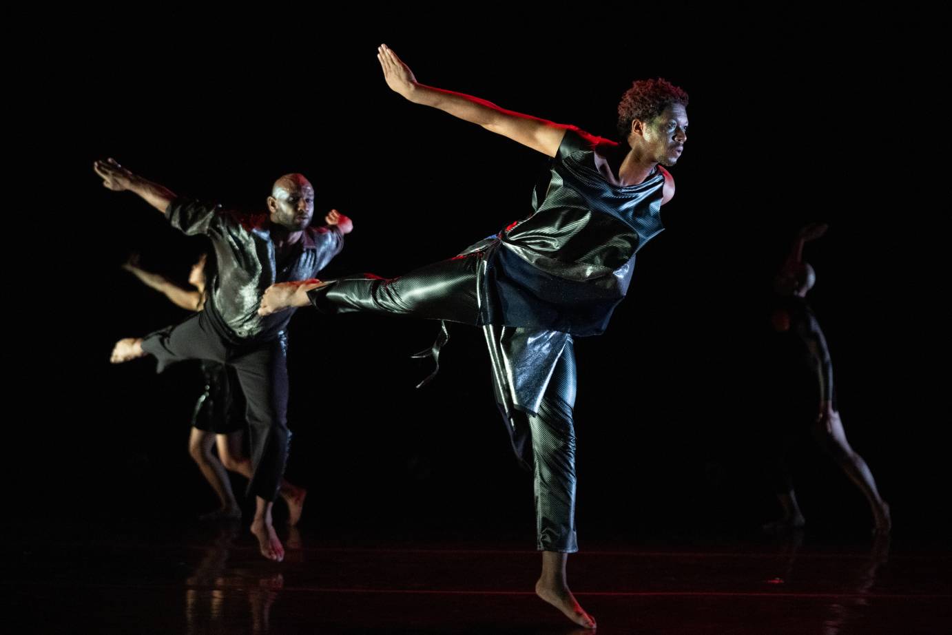 2 male dancers in a jump with one leg and arm extend behind them