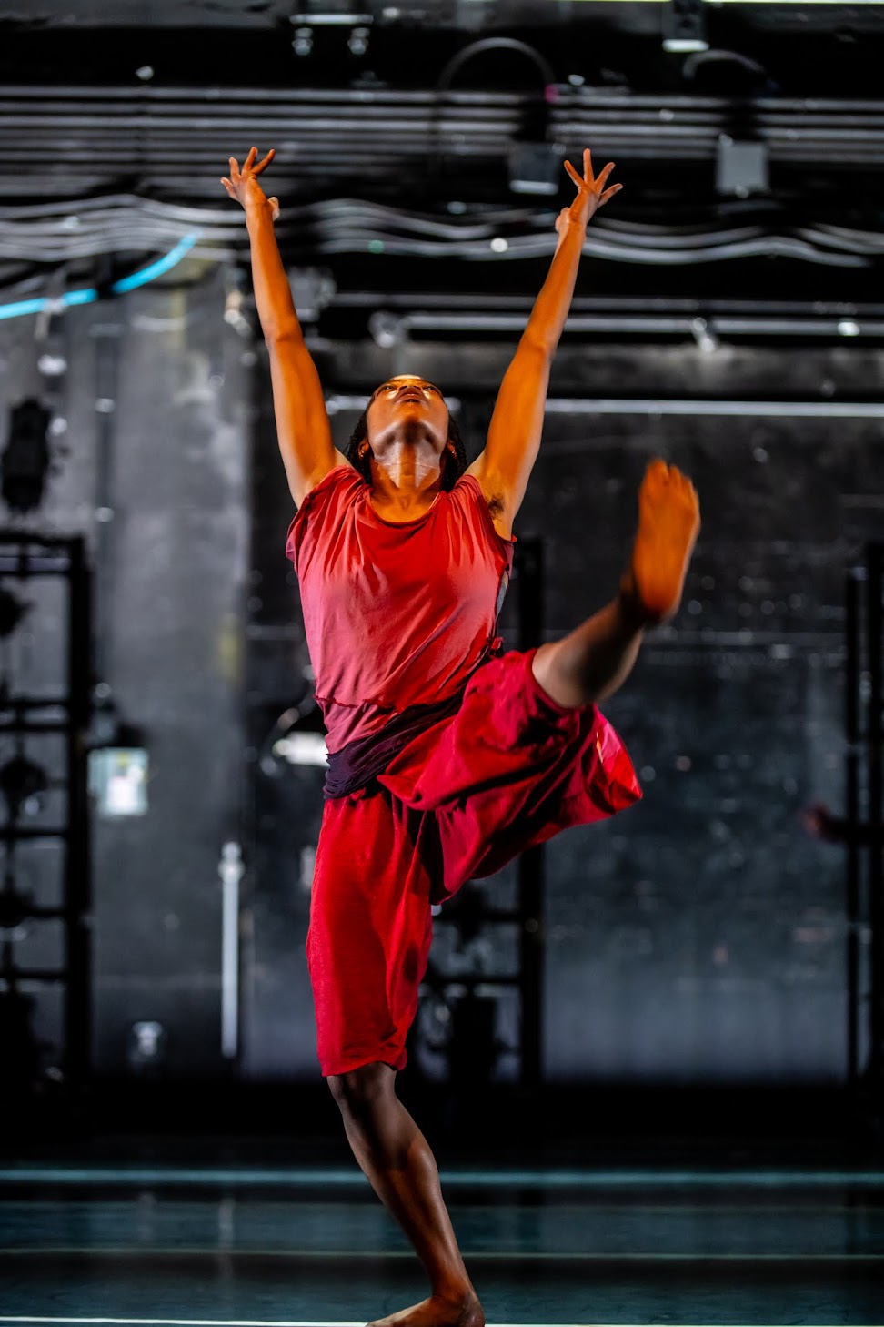Dancer with one leg extended front, both arms and gaze up to sky