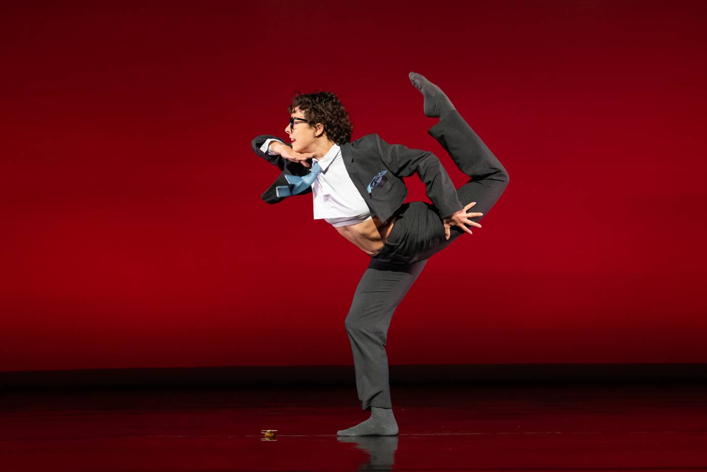 Dancer against a red background in an assymetrical balancing shape