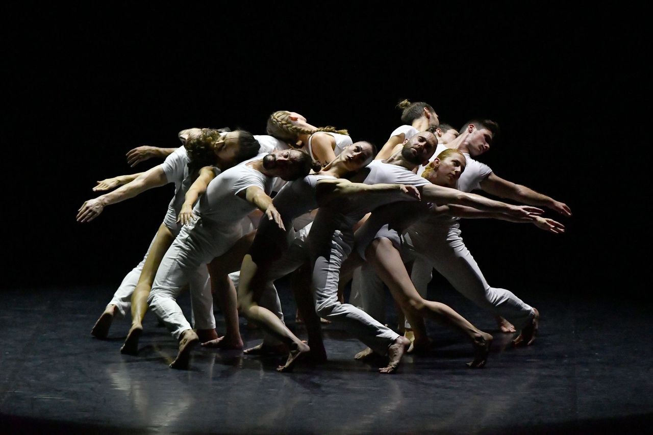 dancers in a circle, heads resting on each others chests as they arch back
