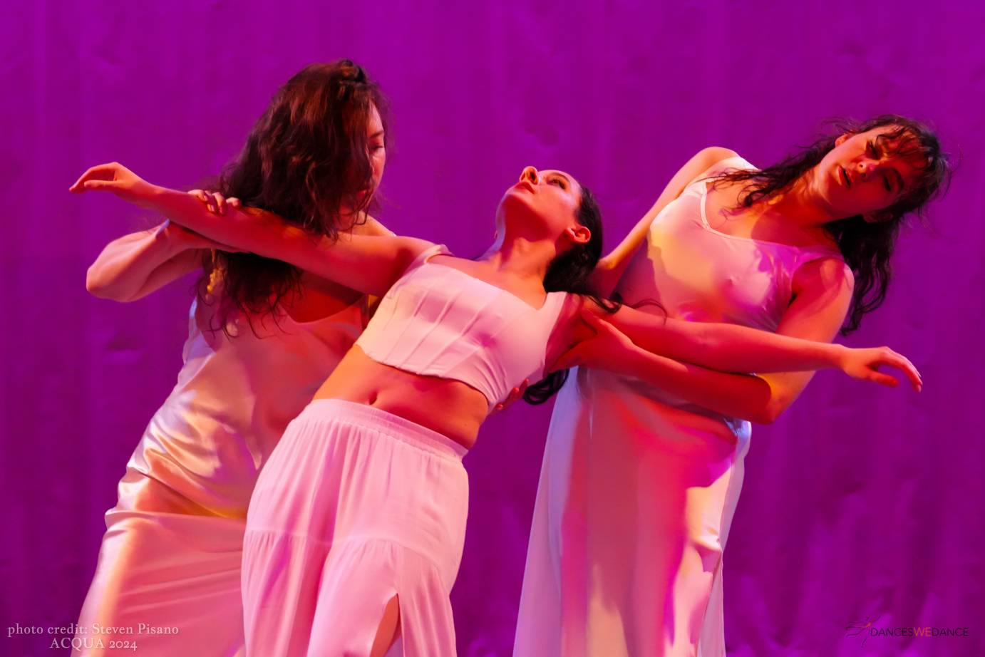 3 female dancers, one with arms outstretched and leaning into the arms of 2 others
