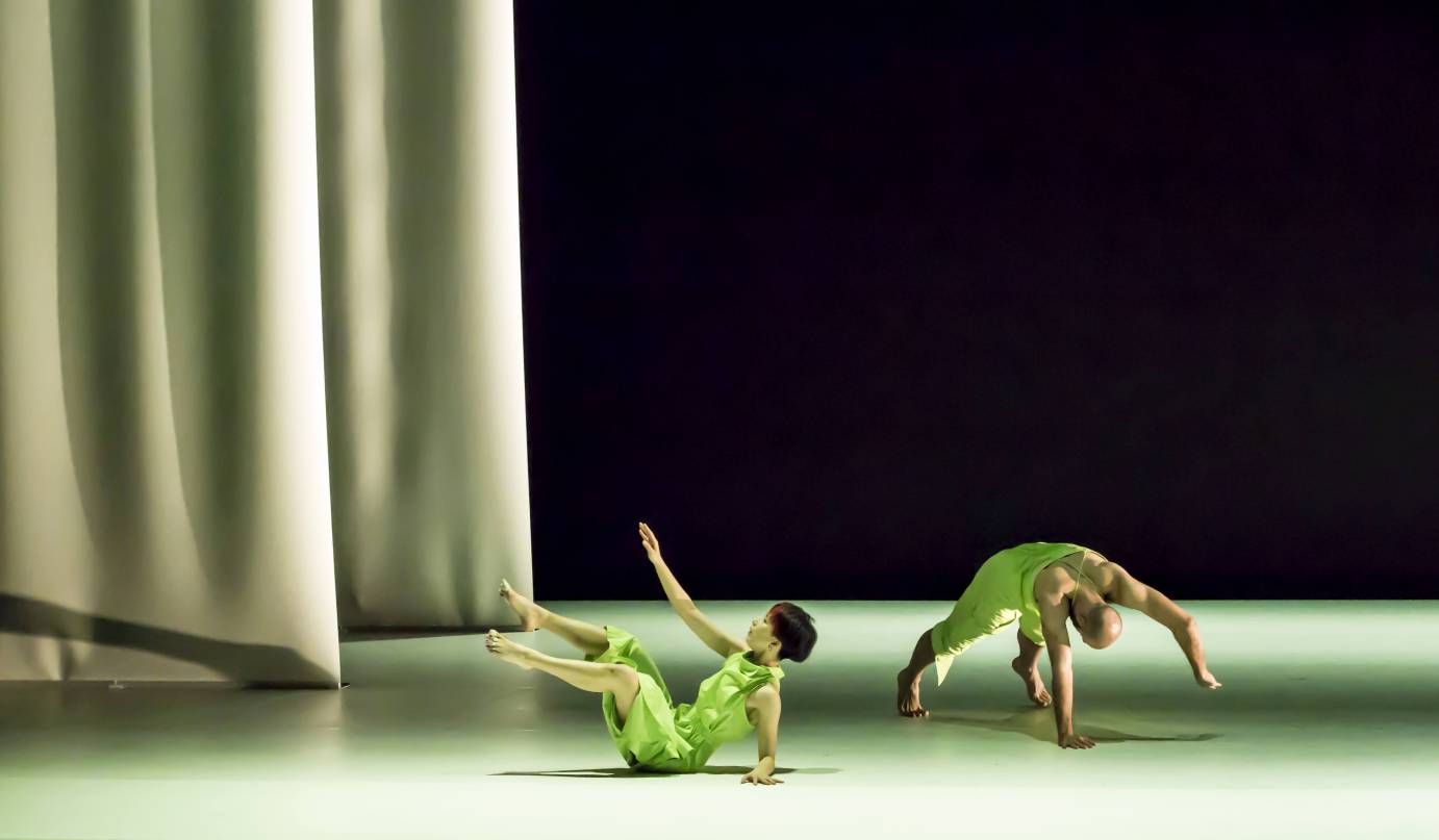 2 dancers, one on floor seated with legs off floor, another in a plank with one arm raised