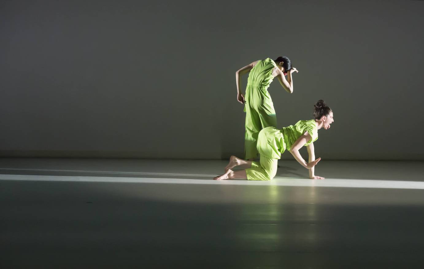 2 dancers close together. one crawling on all 4's, one in a hunched over position