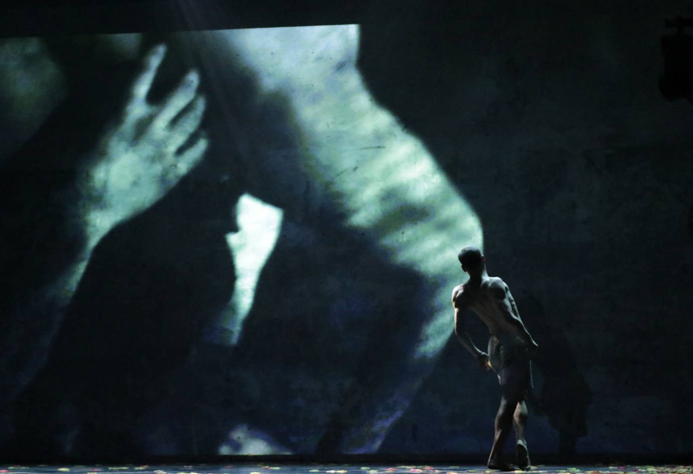 A man leans against a background of limbs in a film