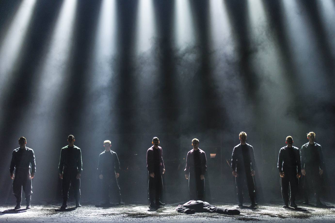 Men stand in a line behind a collapsed body