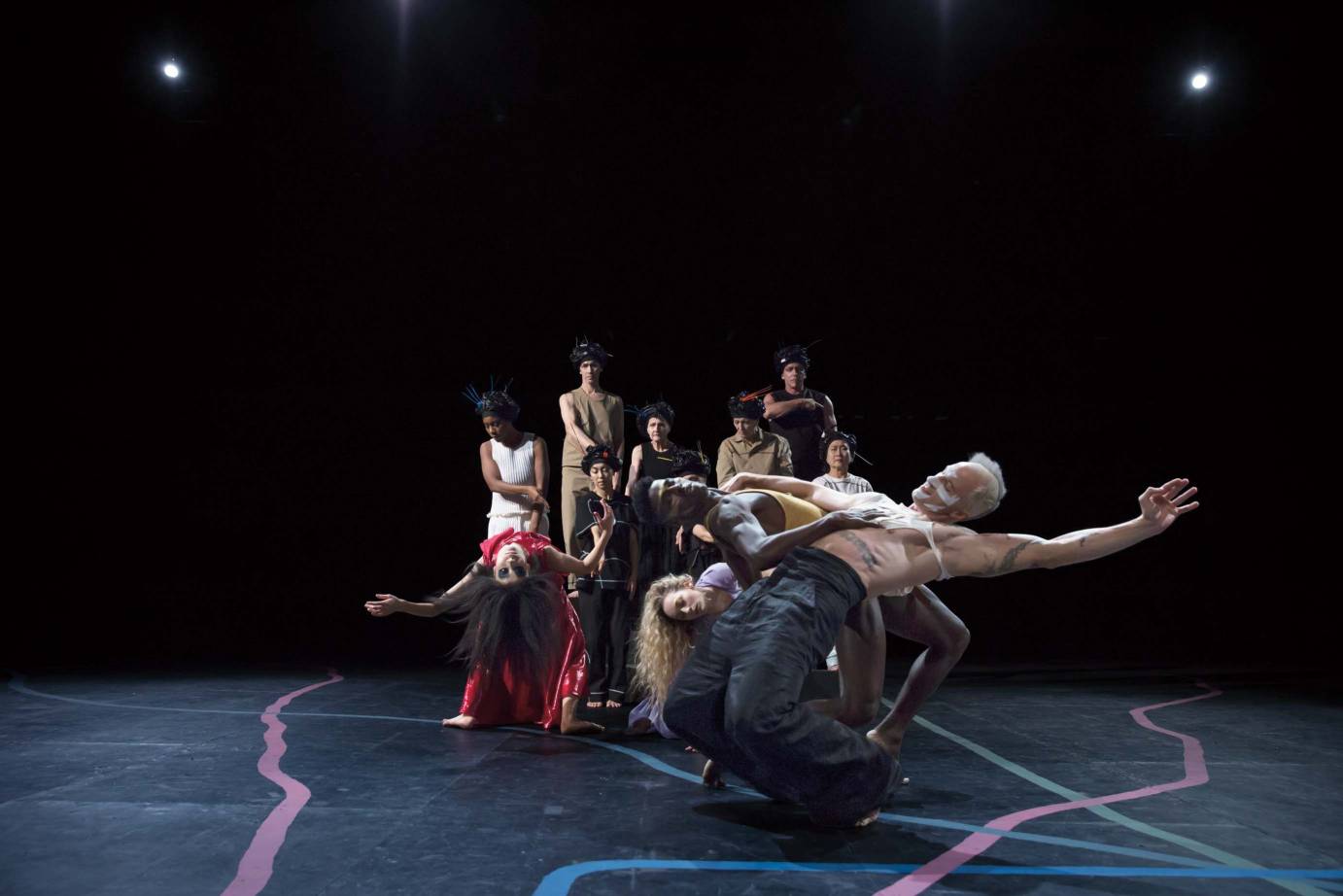 A group of dancers, some bending over backwards, some standing straight.