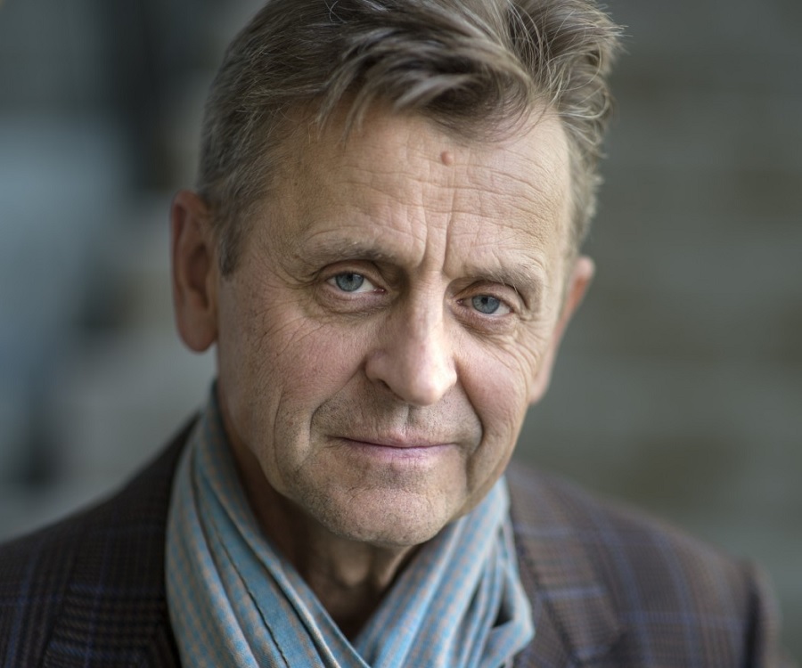 Portrait of Mikhail Baryshnikov wearing a light blue scarf and tartan jacket..