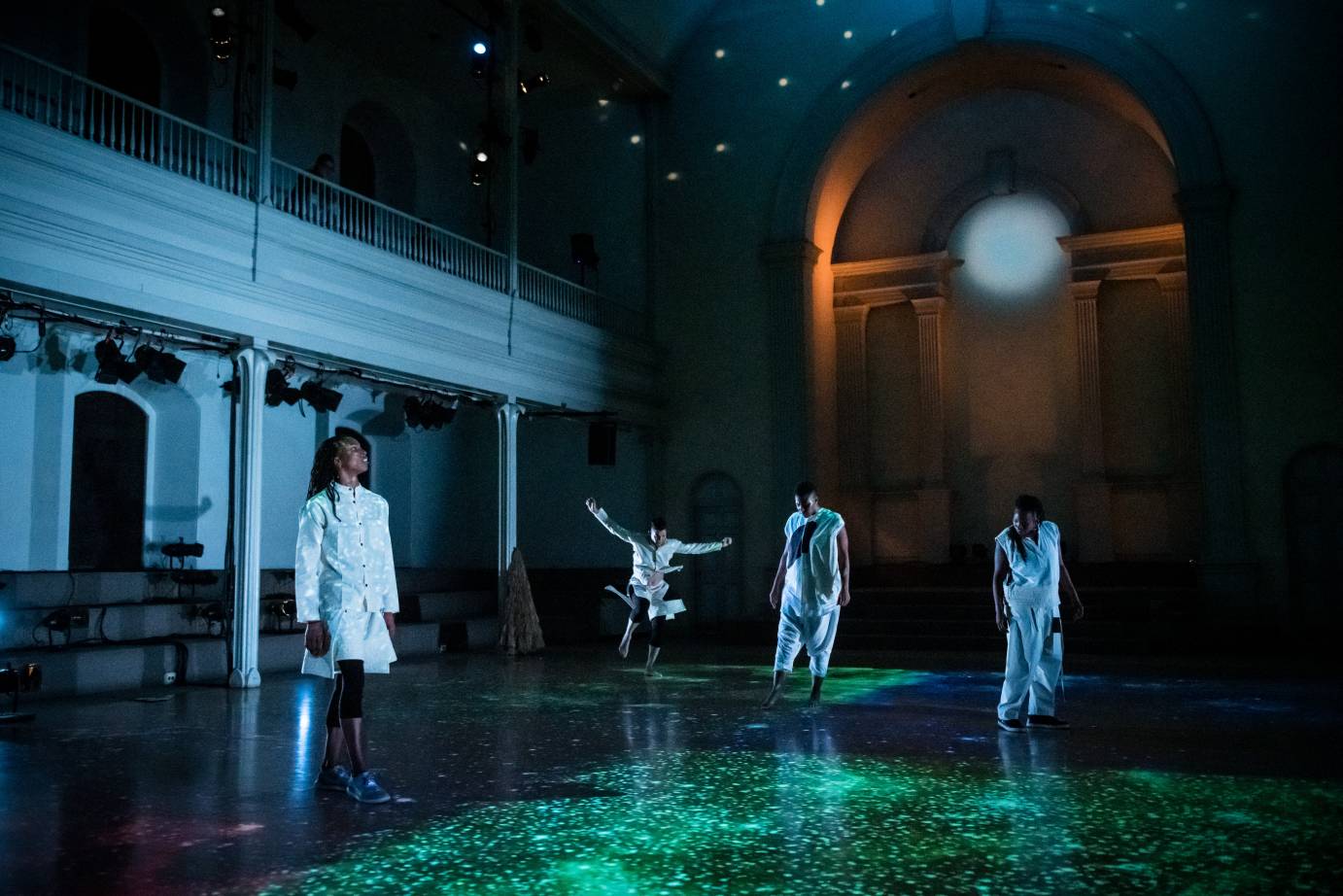 Four dancers in white, one is leaping